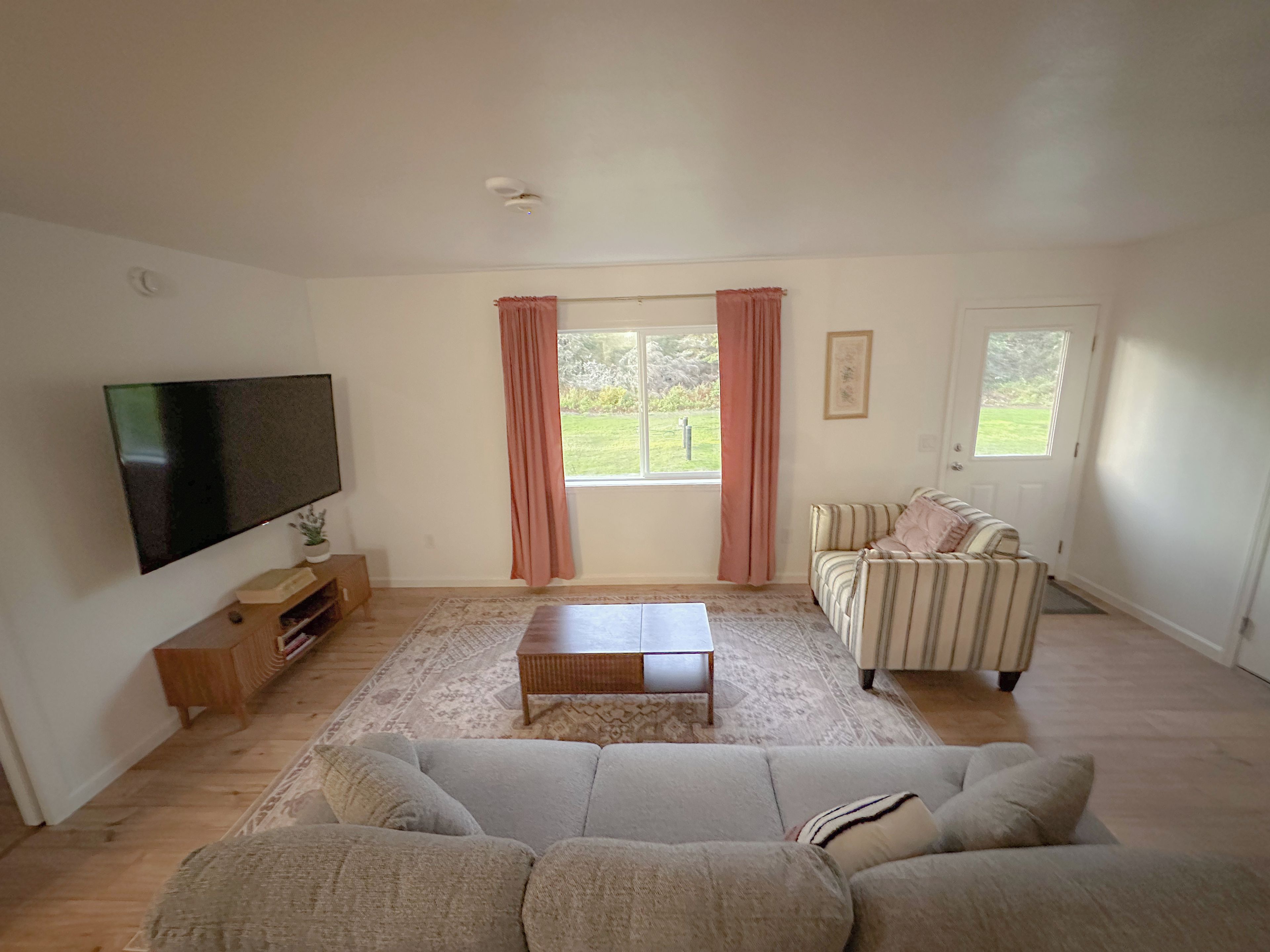 A living room with a flat-screen TV, a sofa, a striped armchair, and a coffee table.