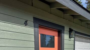 A house with a green siding exterior, a red door, and a garage door.