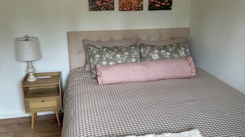 A bedroom with a bed, a nightstand, a lamp, and three wall-mounted paintings.