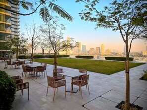 A patio area with outdoor furniture, trees, and a city skyline view.