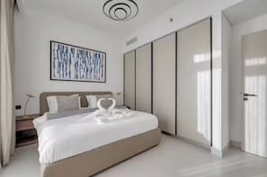 A modern bedroom with a large bed, a wall-mounted artwork, a wardrobe, and a door.