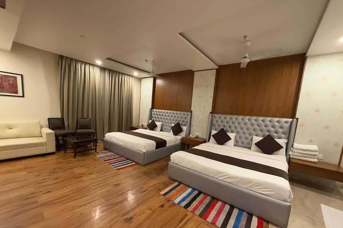Habitació d'hotel amb dos llits, un sofà, una televisió i un escriptori.