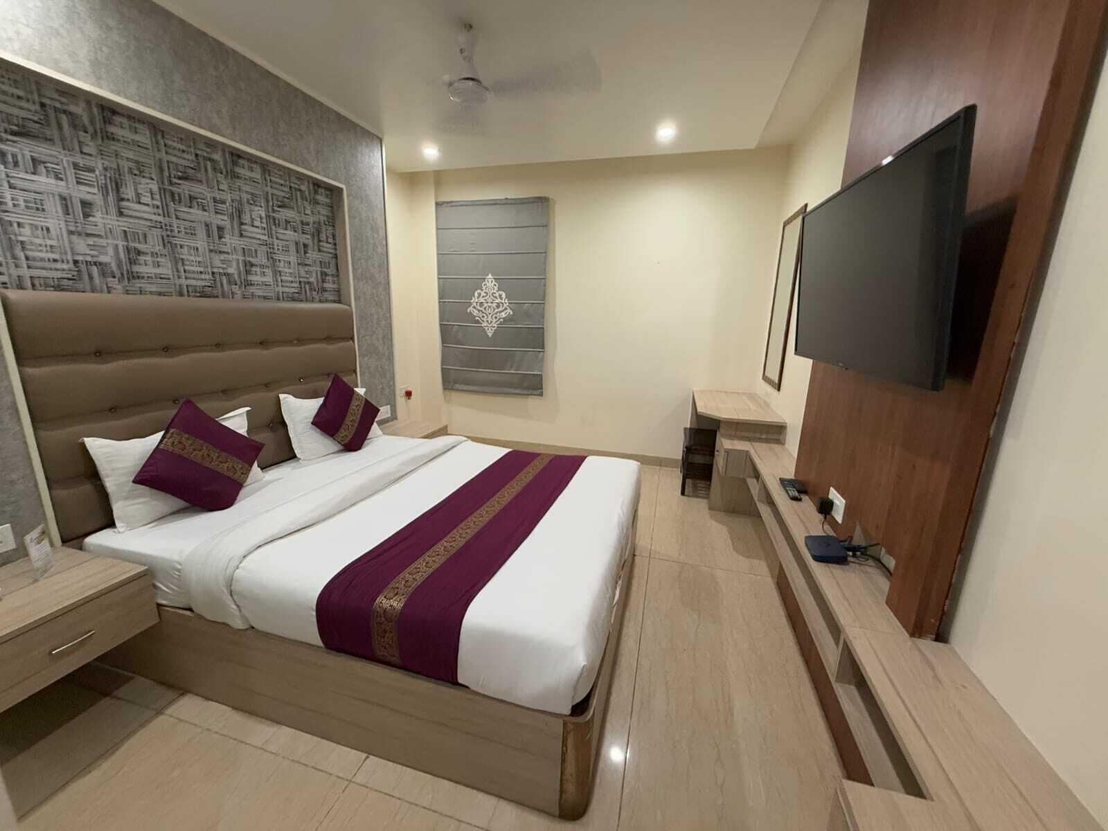 Una habitación de hotel moderna con una cama grande, un televisor de pantalla plana, un escritorio y un panel decorativo en la pared.