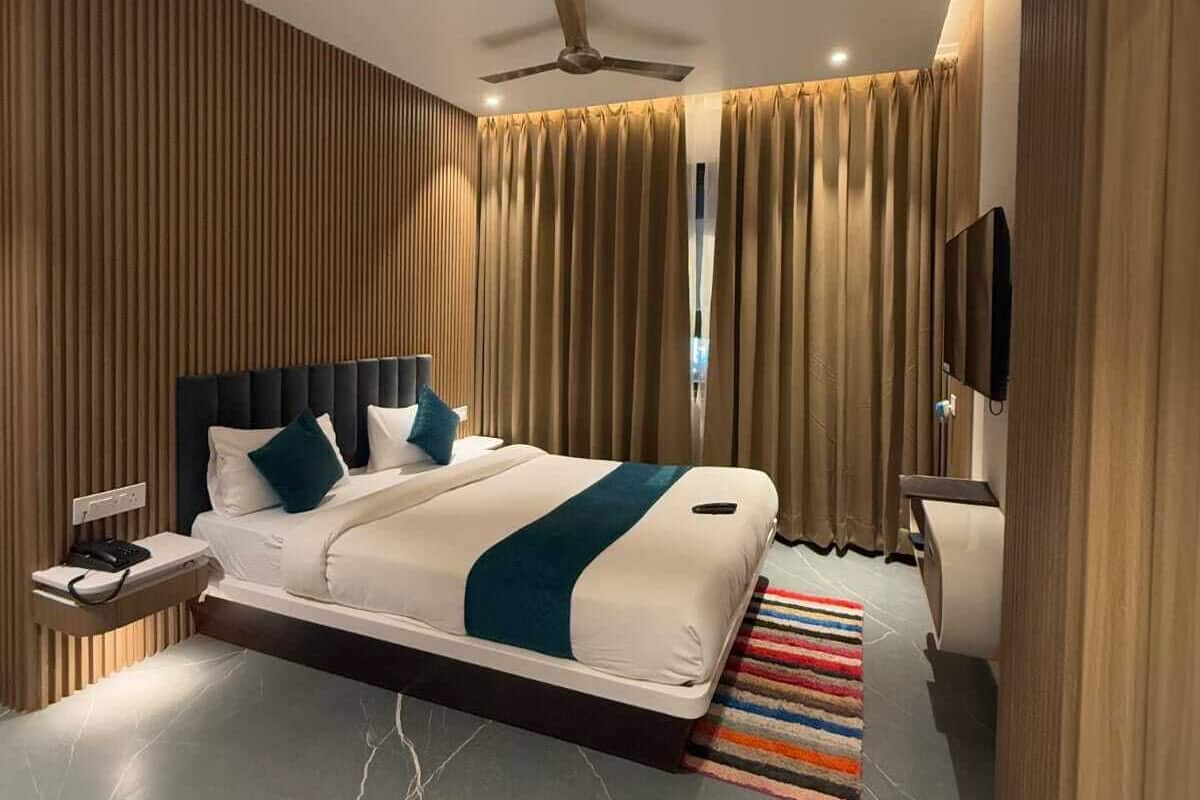 Habitació d'hotel moderna amb un llit, una taula de nit, un televisor i un ventilador de sostre.