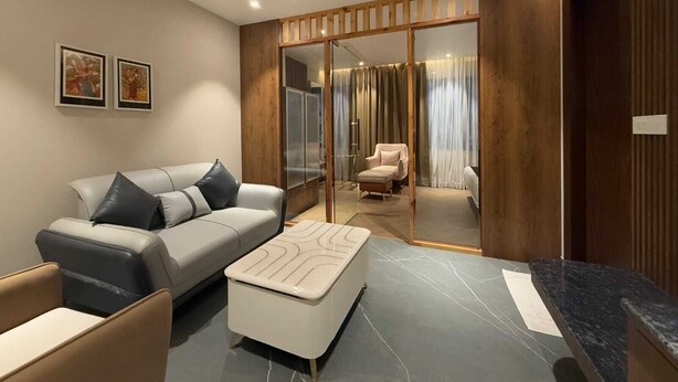 Uma sala de estar moderna com sofá, puf e uma divisória de vidro com porta deslizante.