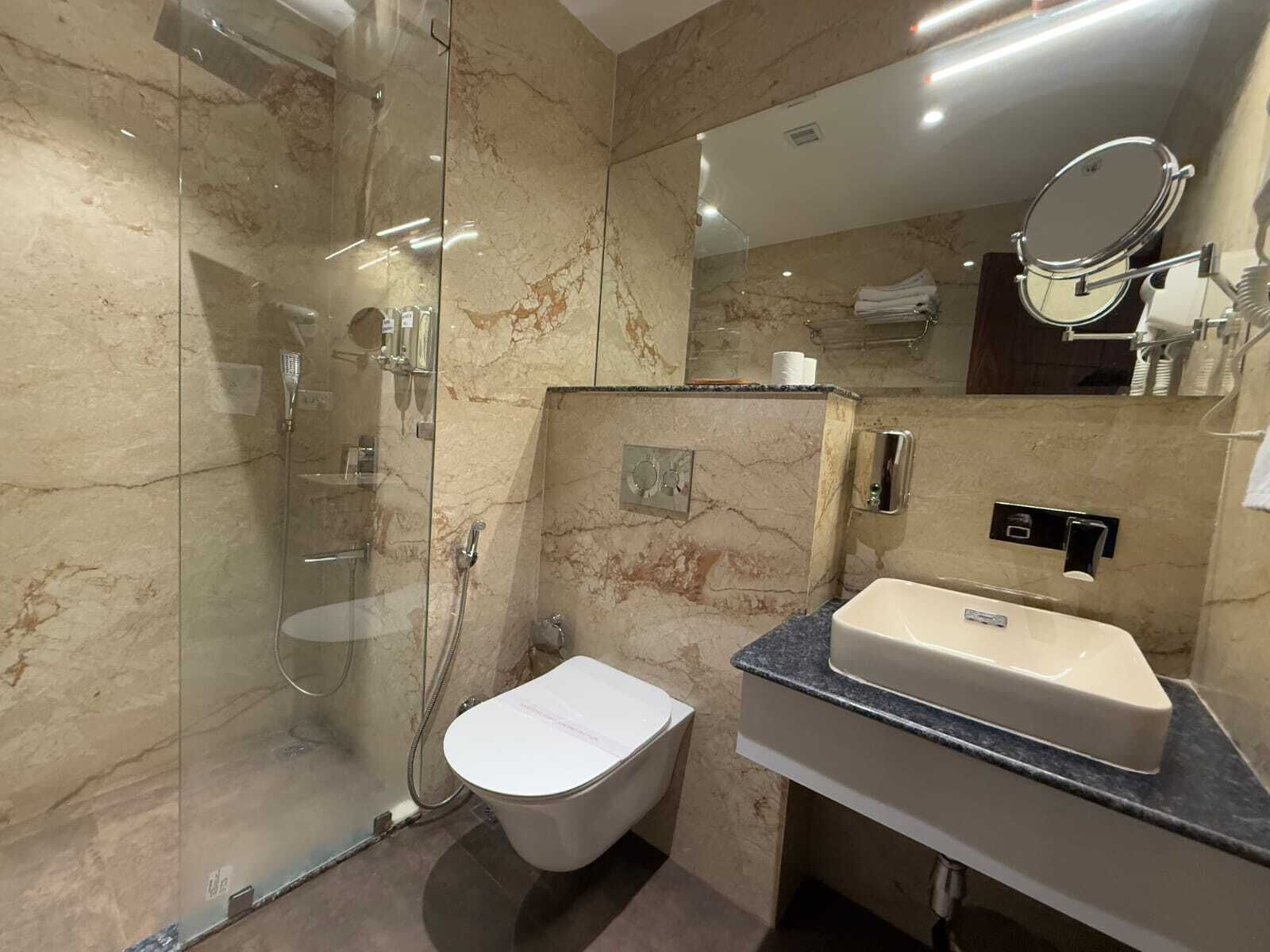 Un baño moderno con ducha envuelta en vidrio, inodoro y tocador con lavamanos.
