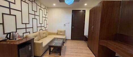 A modern living room with a sofa, coffee table, wooden cabinet, and a decorative wall panel.