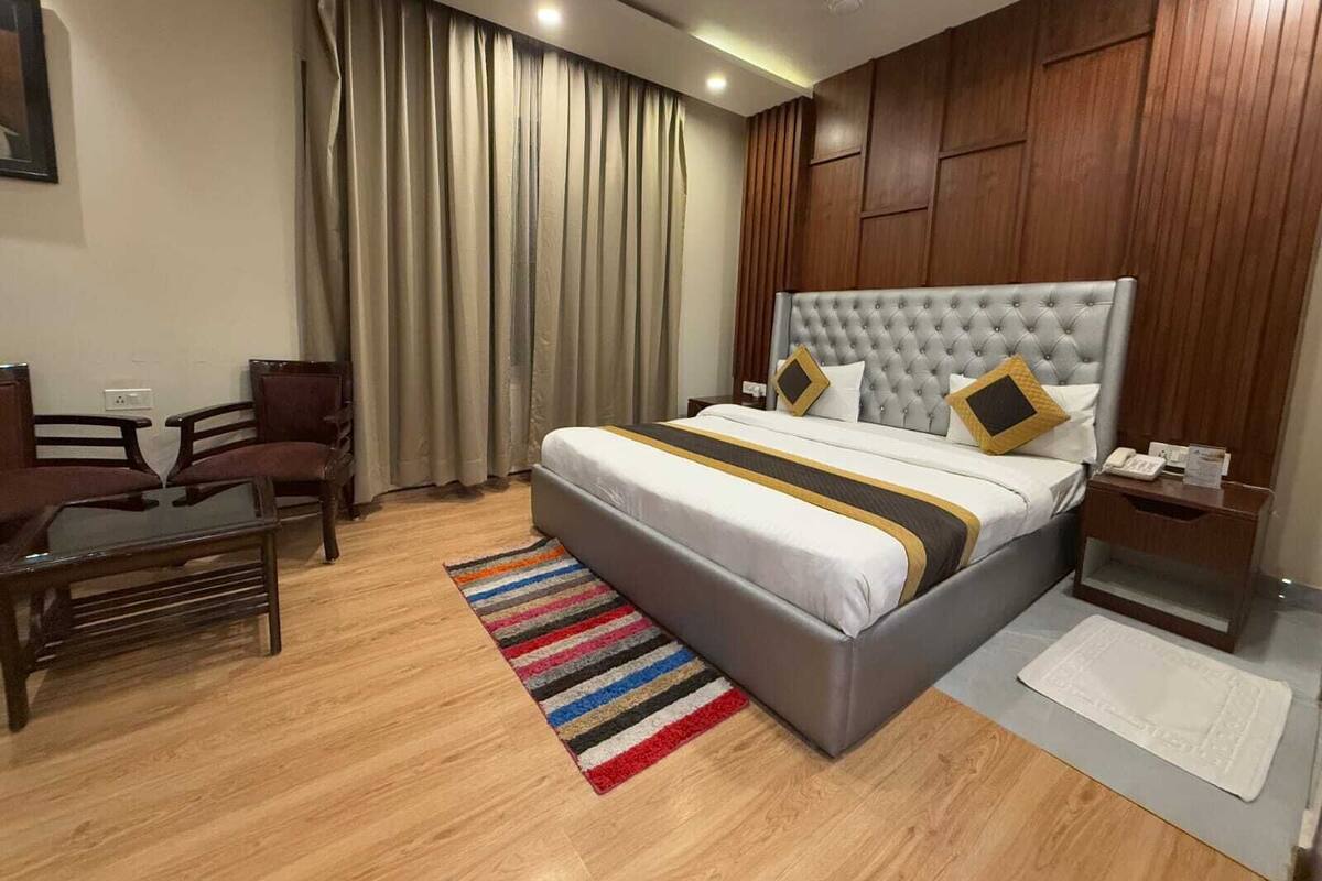 Habitació d'hotel amb un llit gran, una taula de treball, una cadira i una finestra amb cortines.