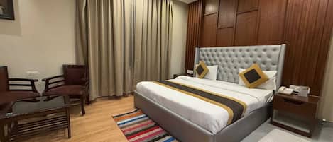 Una habitación de hotel con una cama grande, un escritorio, una silla y una ventana con cortinas.