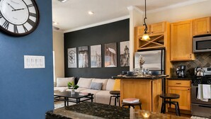 Une cuisine moderne avec un îlot central, des meubles en bois, un four à micro-ondes et une horloge au mur.