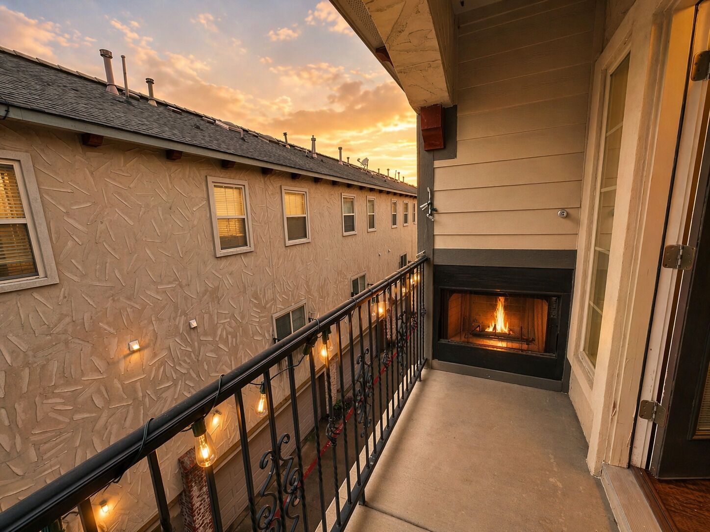 Un balcone con un camino, una ringhiera illuminata e un edificio con finestre.