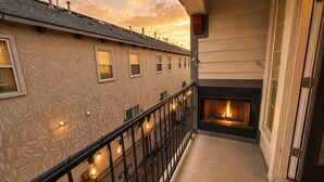 Un balcon doté d’une cheminée, une balustrade ornée de lumières et un immeuble avec des fenêtres.