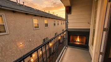 Un balcone con un camino, una ringhiera illuminata e un edificio con finestre.