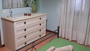 A room with a bed, a dresser, a mirror, and a window with curtains. - Cottage a stone's throw from the sea (San Vito Lo Capo)