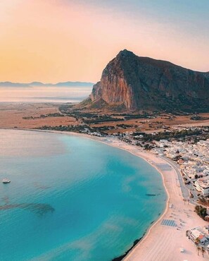Une ville côtière dominée par une montagne imposante, avec une plage et une mer calme.