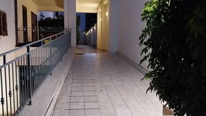 A corridor with tiled flooring, a metal railing, and a plant on the right. - Cottage a stone's throw from the sea (San Vito Lo Capo)