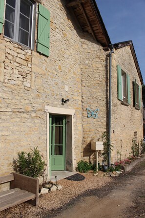 A stone building with a green door, a butterfly decoration, and a bench outside. - Gite La Salamandre (Saint-Vincent-de-Cosse)