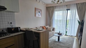 A compact kitchen with a microwave, a stove, and a dining area with a table and chairs. - Ideal Homes by Lyn is an executive 1 bedroom bnb located at the heart of Nairobi (Nairobi)