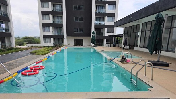 A swimming pool with safety rings, a ladder, and a statue in the background. - Ideal Homes by Lyn is an executive 1 bedroom bnb located at the heart of Nairobi (Nairobi)