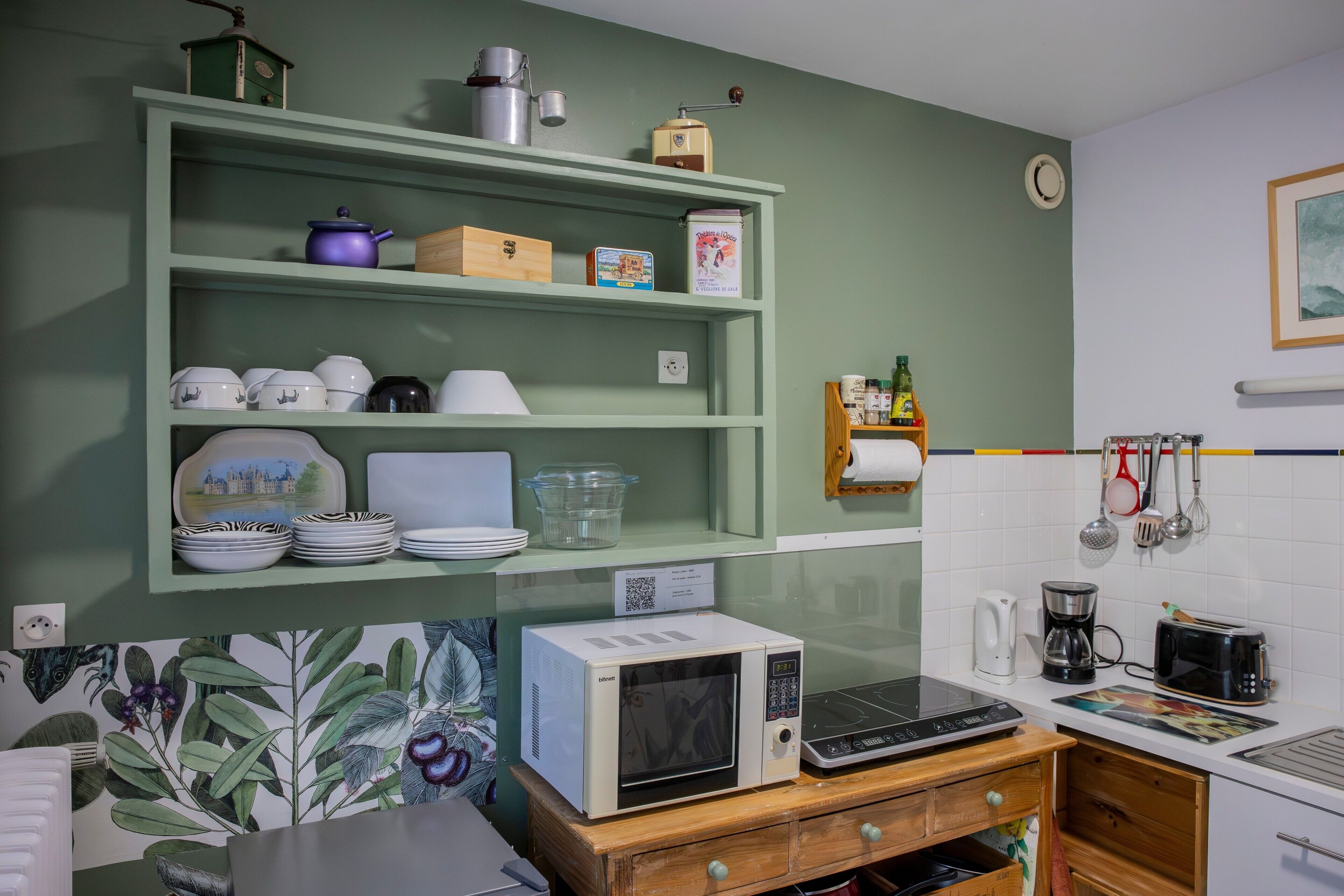 Eine Küche mit Mikrowelle, Toaster und verschiedenen Küchenutensilien in Regalen.