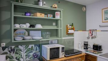 Eine Küche mit Mikrowelle, Toaster und verschiedenen Küchenutensilien in Regalen.