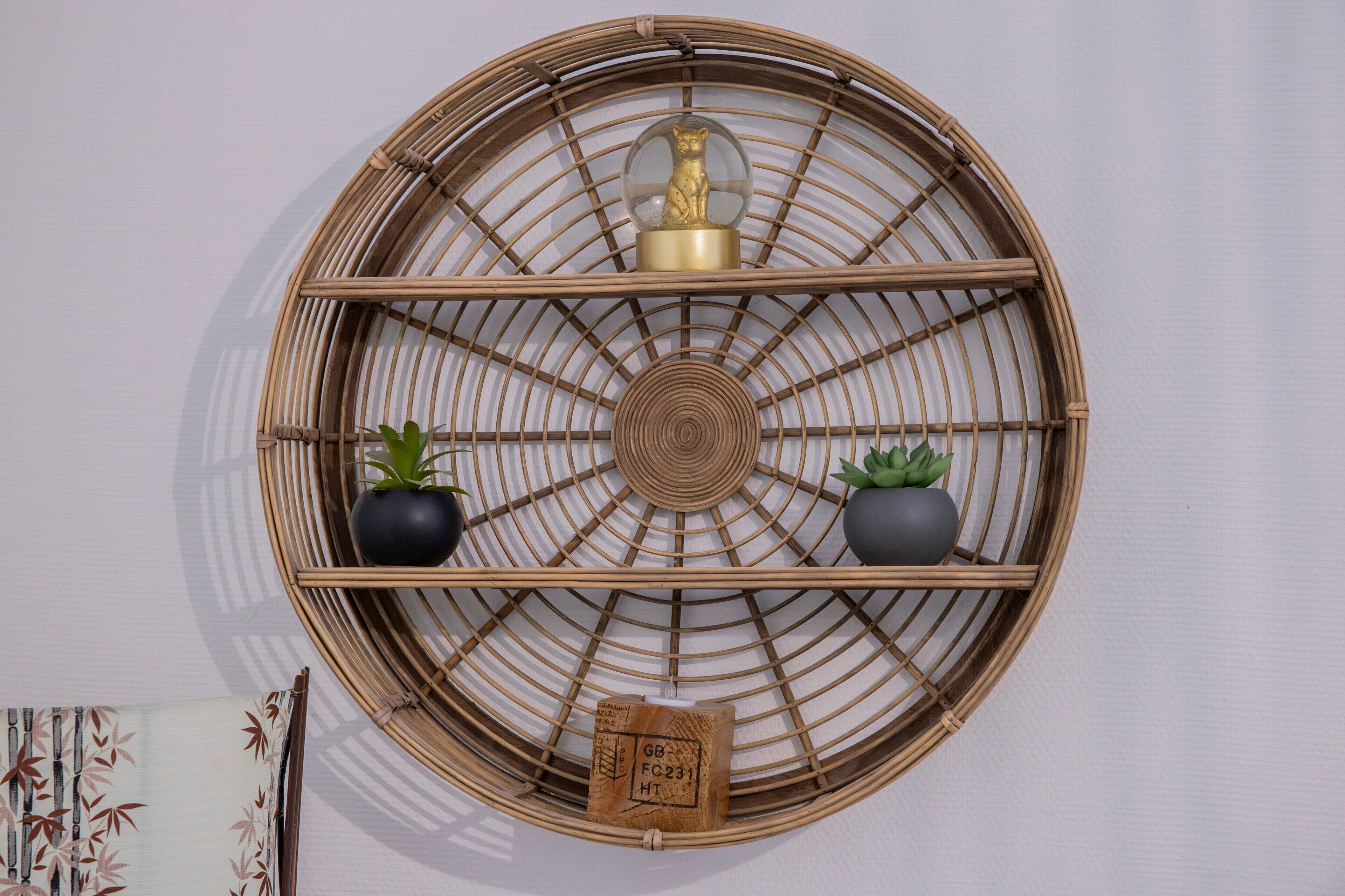 Een ronde bamboeplank met een wereldbol ornament, twee potplanten en een klein vierkant lijstje.