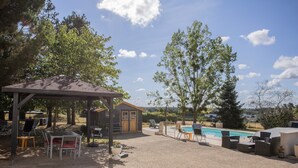 Un patio techado con mobiliario exterior, un cobertizo pequeño y una piscina.