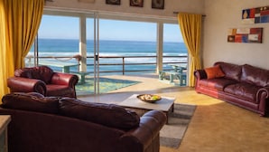 Ein Wohnzimmer mit Meerblick, Ledersofas, einem Couchtisch und Kunstwerken an der Wand.