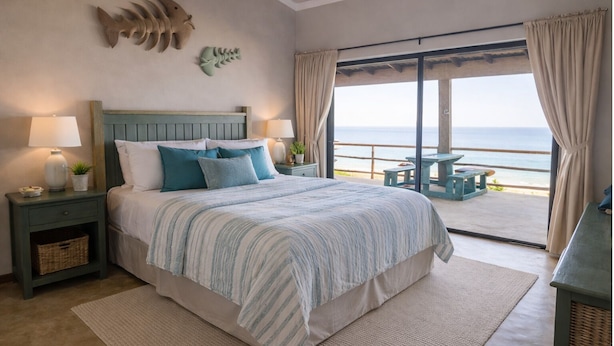 Ein Schlafzimmer mit Bett, Nachttischen, Meerblick und einem Balkon mit Tisch.