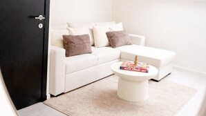 Ein modernes Wohnzimmer mit einem weißen Sofa, einem Couchtisch und einer schwarzen Tür.