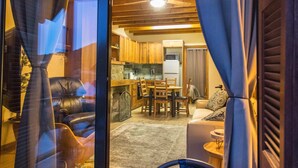 A cozy interior with a dining area, kitchen, and a view through a glass door. - Cozy mountain apartment in Platres (Pano Platres)