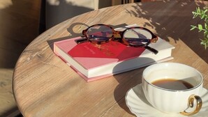 A round wooden table with a book, glasses, and a cup of coffee. - Cozy mountain apartment in Platres (Pano Platres)