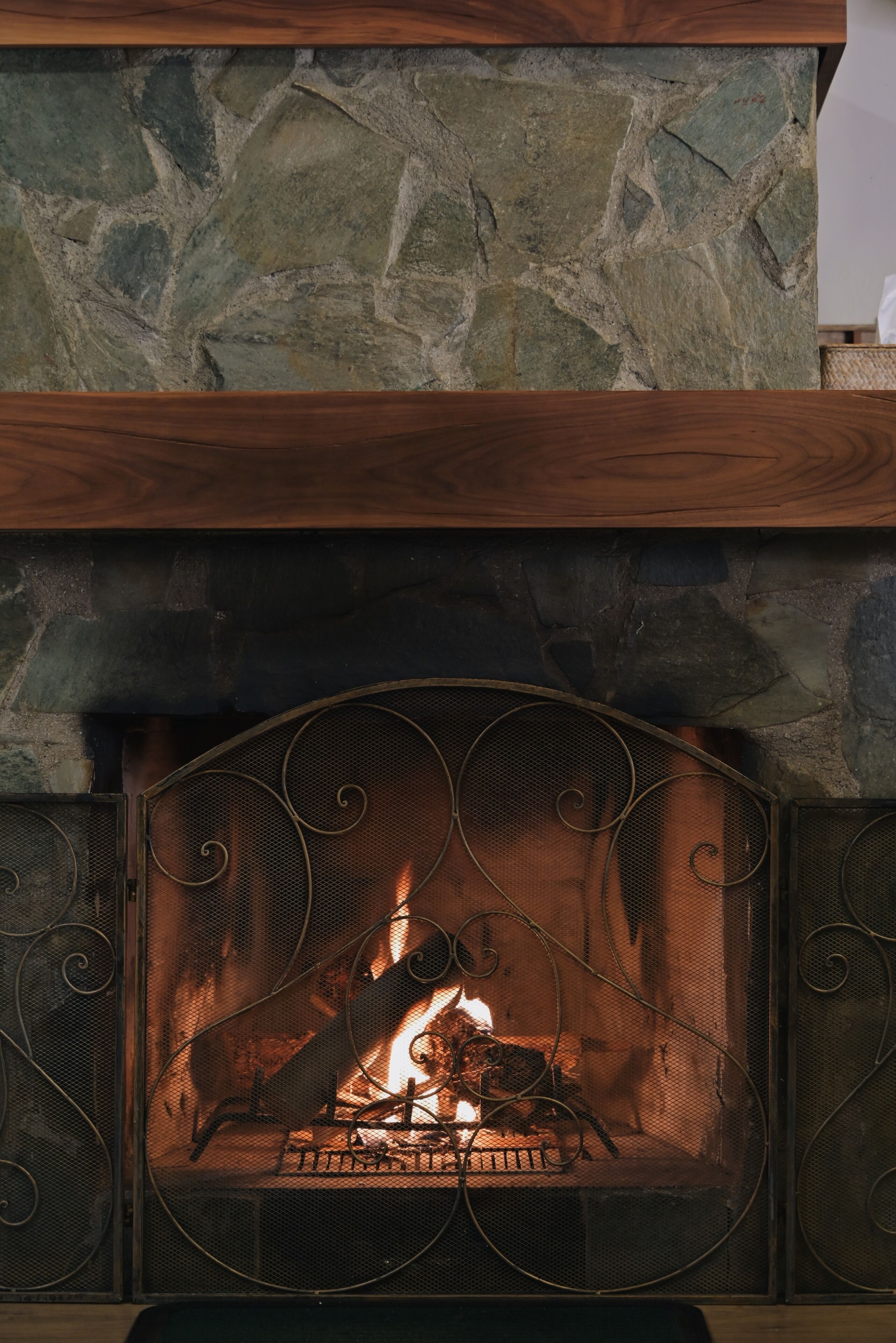 A fireplace with a stone surround and a metal grate.