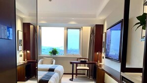A hotel room with a large bed, a desk, a chair, a TV, and a window with a view. - Beijing Ningxia Hotel (Beijing)