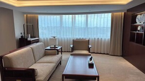 A hotel room with a sofa, armchair, coffee table, and a large window with curtains. - Beijing Ningxia Hotel (Beijing)