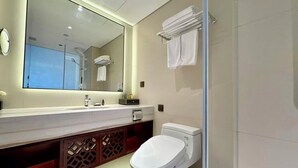 A modern bathroom with a large mirror, a white toilet, a sink with a towel rack, and a shower area. - Beijing Ningxia Hotel (Beijing)