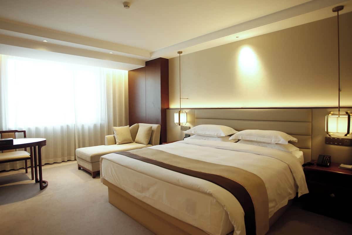 A hotel room with a large bed, a desk, and a chair.