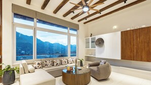 A modern living room with a large window, a round coffee table, and a sofa. - ELIVAAS Antarmann Casa Zenith 6 BHK (Bhimtal)