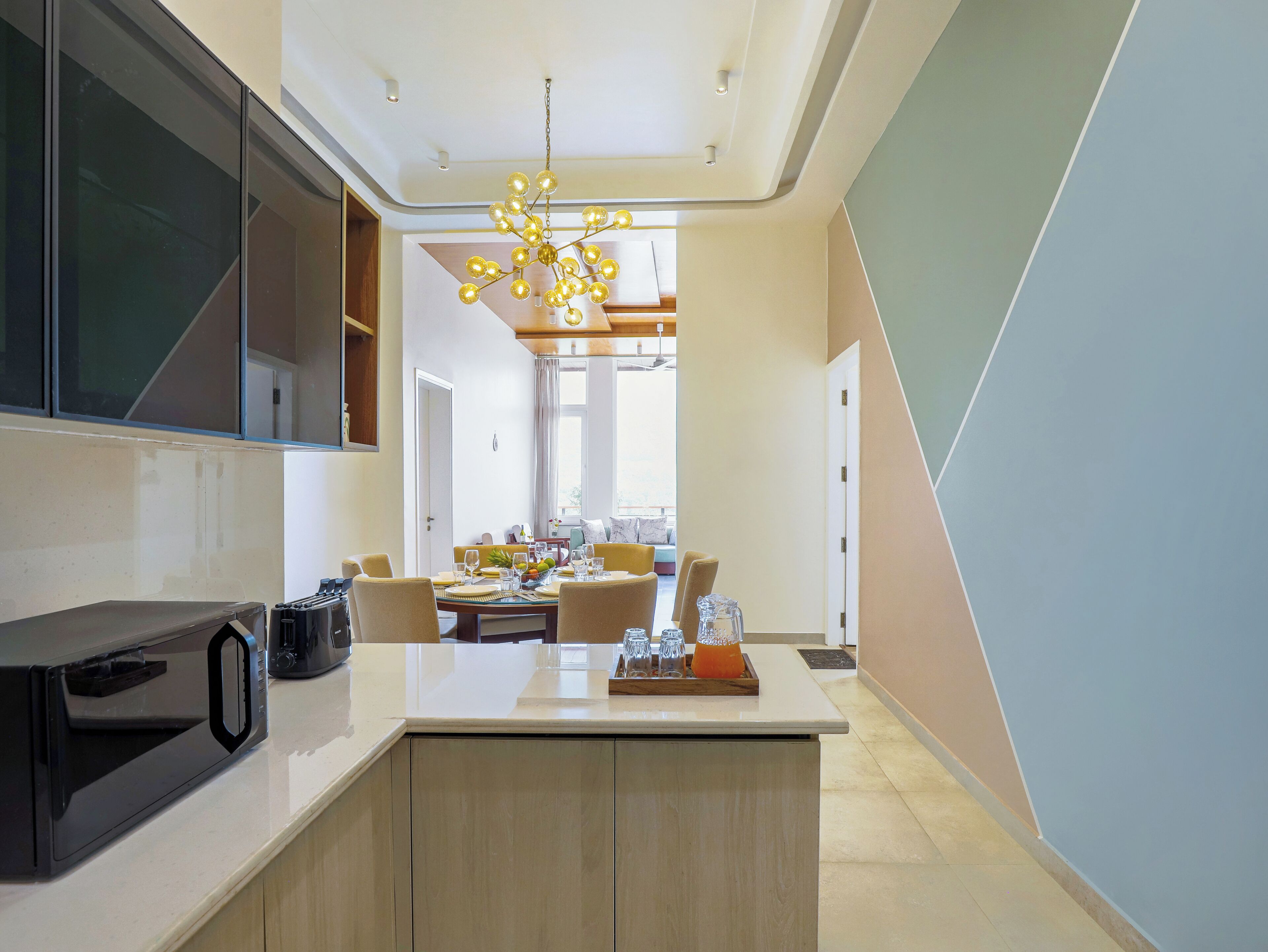 A modern kitchen with a built-in microwave, a central island with seating, and a dining area in the background.