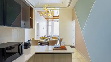 A modern kitchen with a built-in microwave, a central island with seating, and a dining area in the background.