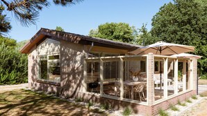 Une maison dotée d’un patio couvert, de grandes fenêtres et d’une façade en briques.