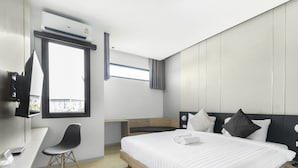 A modern hotel room with a bed, a desk, a chair, a window, and an air conditioning unit. - B48 Hotel (Bangkok)