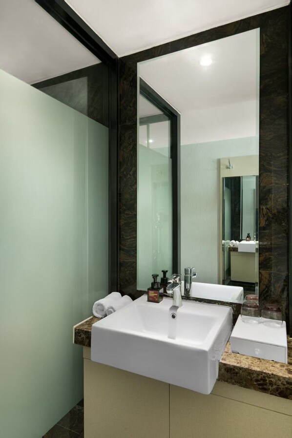 A modern bathroom with a large mirror, a white sink, and a glass shower enclosure.