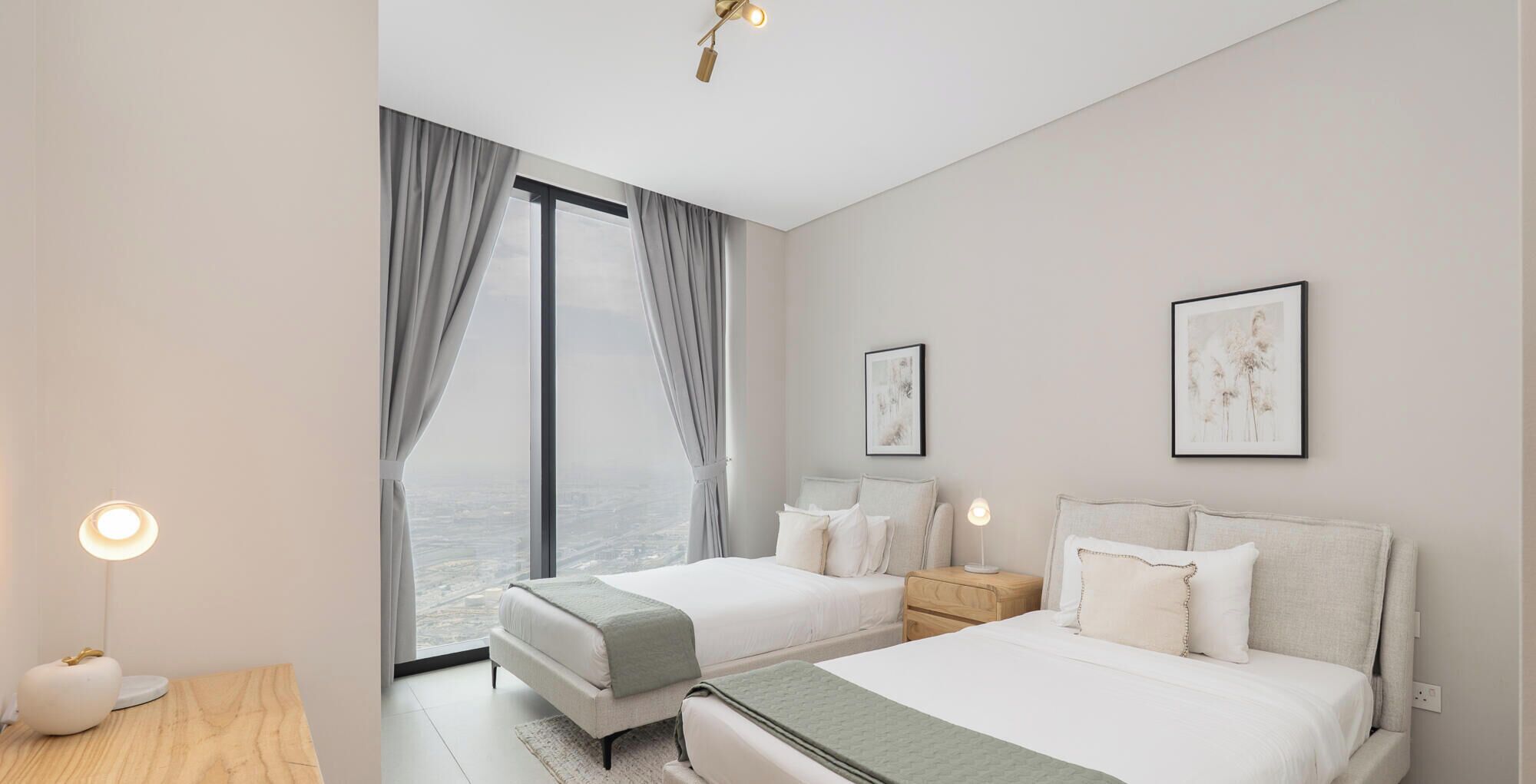 A modern hotel room with a large window, two beds, a bedside table, and a nightstand.