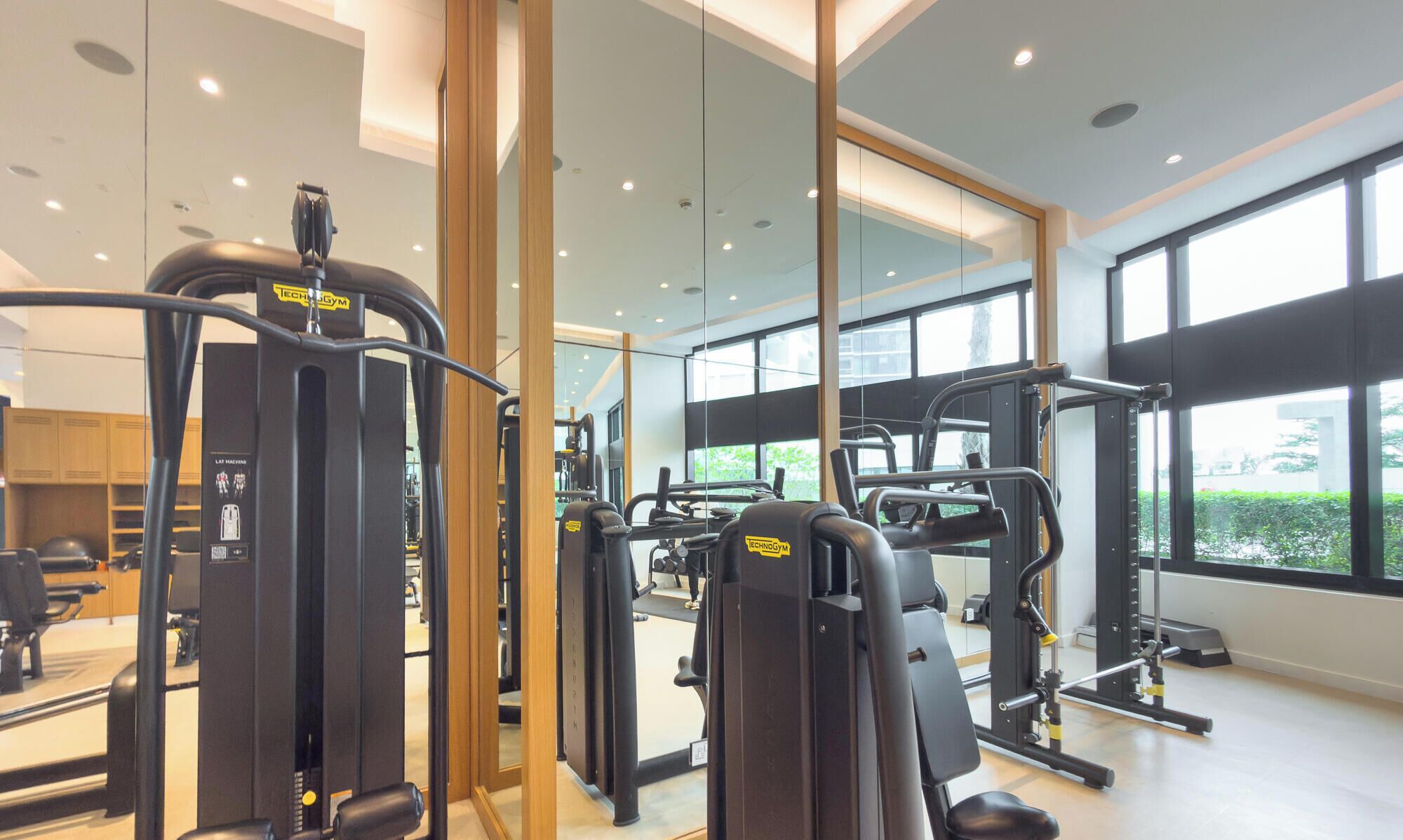 Een moderne sportschool met diverse fitnessapparaten, grote ramen en een schoon, goed verlicht interieur.