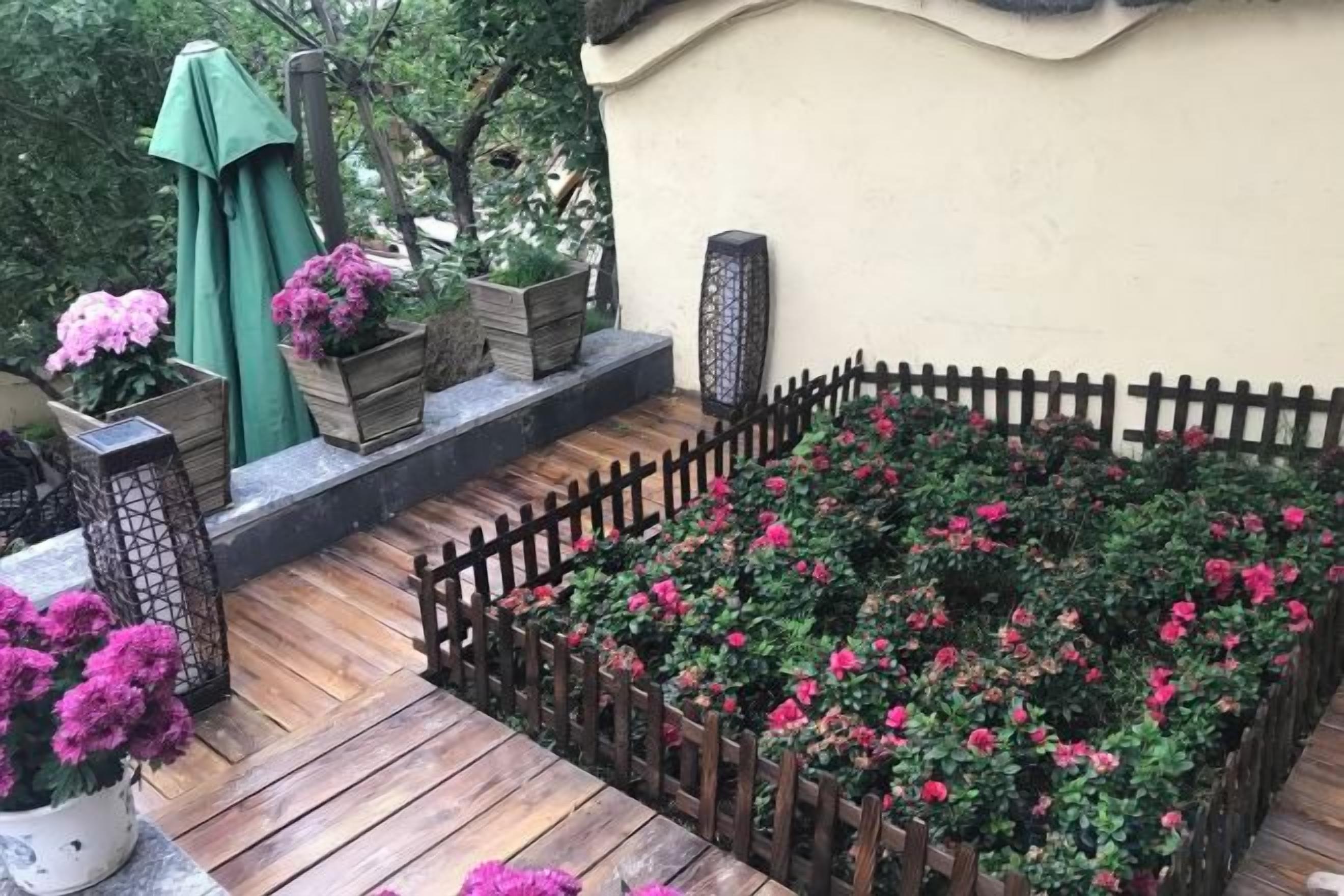 A wooden deck with raised flower beds, a wooden fence, and potted plants.