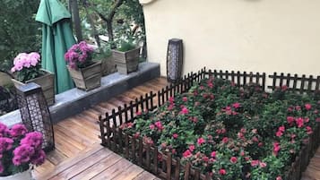 A wooden deck with raised flower beds, a wooden fence, and potted plants.