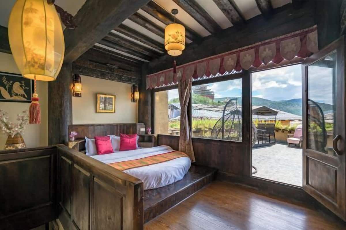 Une chambre à coucher avec un lit en bois, une grande fenêtre et une vue sur l’extérieur.