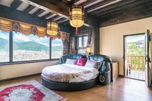 Een slaapkamer met een rond bed, grote ramen en uitzicht op de omgeving.