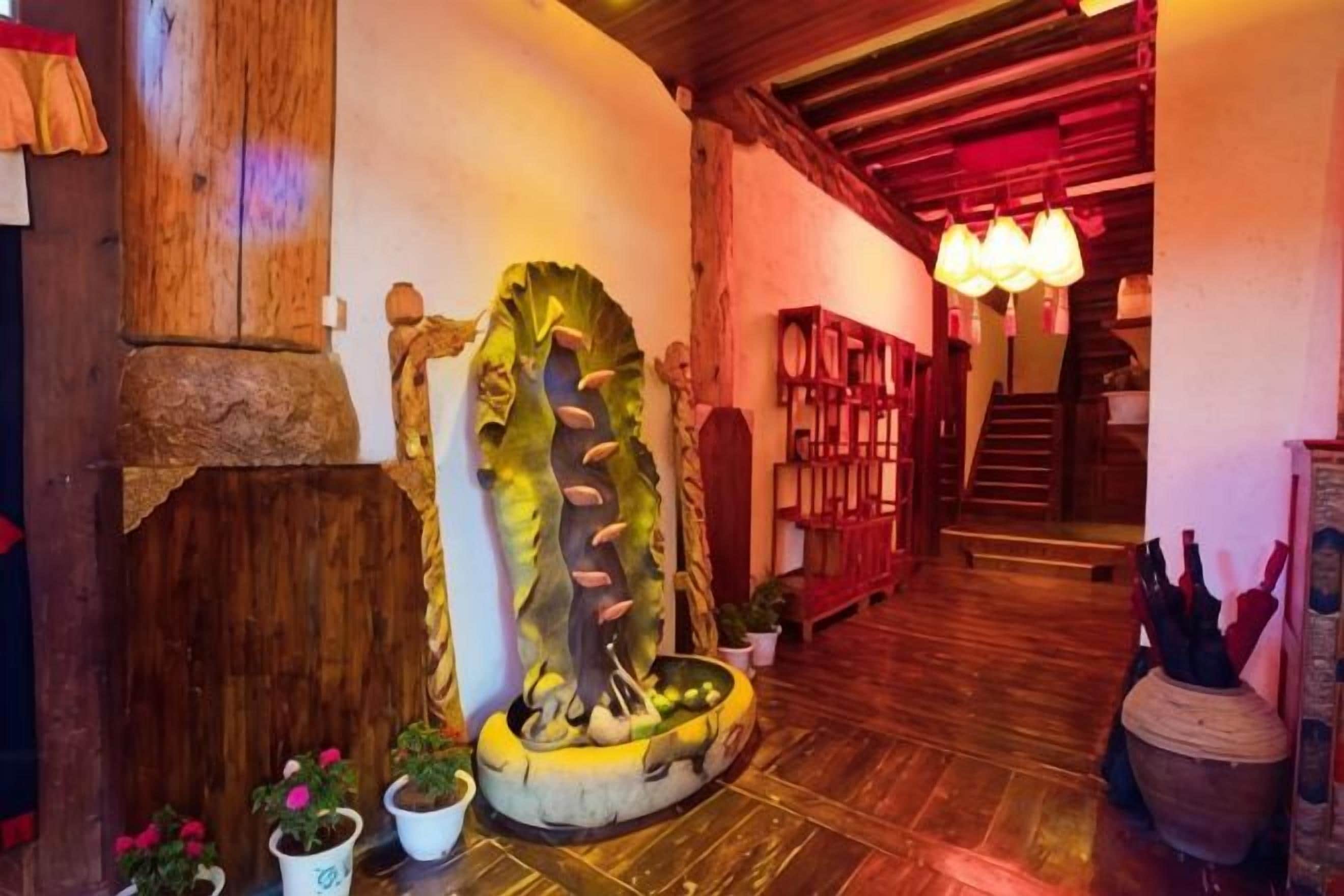 Ein Holzinterieur mit einer Treppe, einer großen Zimmerpflanze und einem Chandelier.